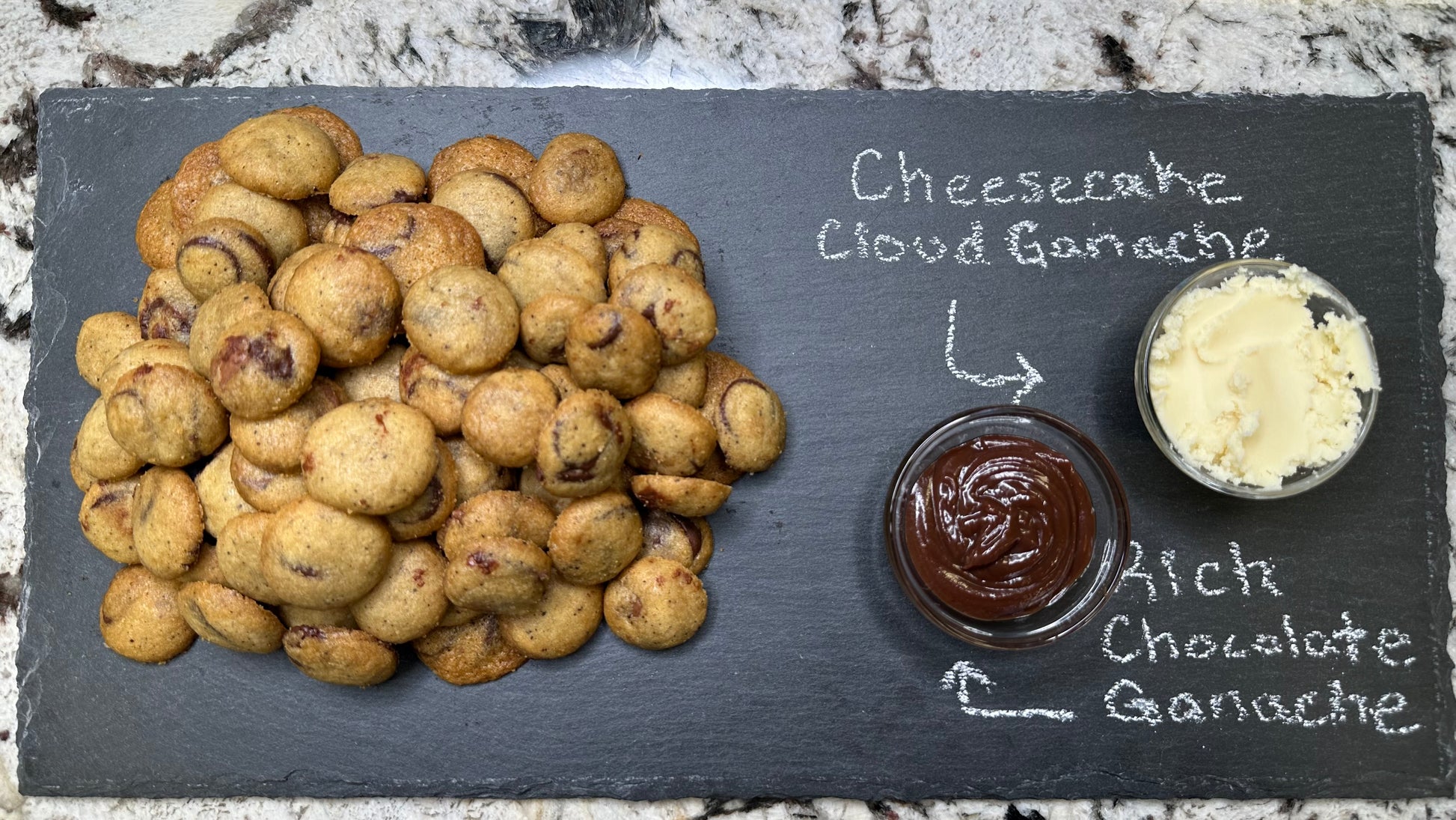 Cookies with cheesecake cloud ganache, and rich chocolate ganache on a slate board.
